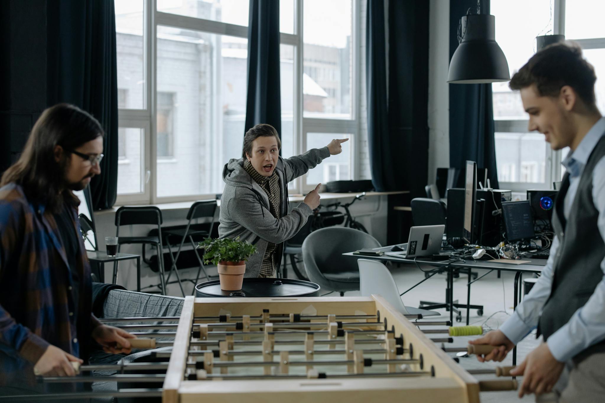 Professionals engaged in a foosball game in a modern office, highlighting relaxation and teamwork.