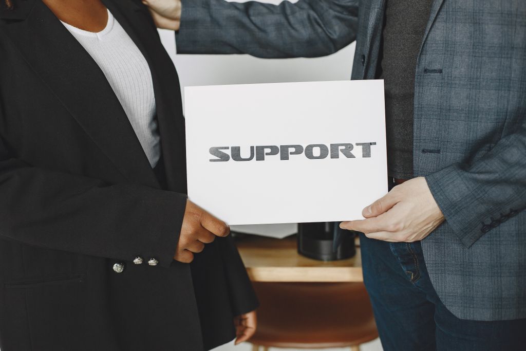 Ryhmä ammattilaisia pitelee kylttiä, jossa lukee support